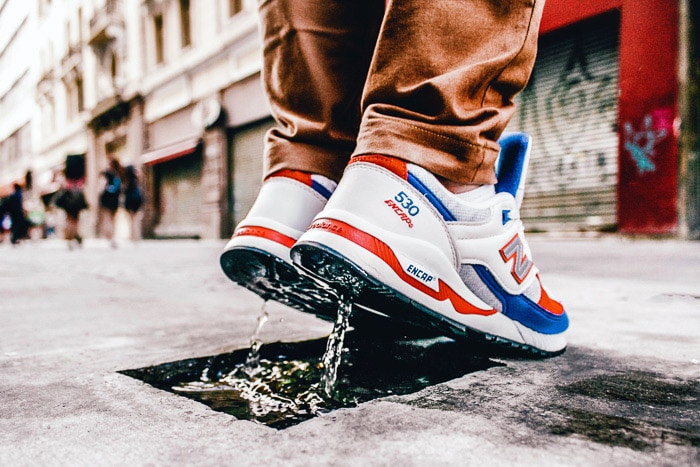 Close up foto van een persoon in sportschoenen die in een kleine plas op straat springt met een snelle sluitertijd