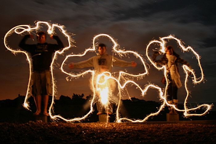 Drie mensen omringd door nachtelijk lichtschilderij