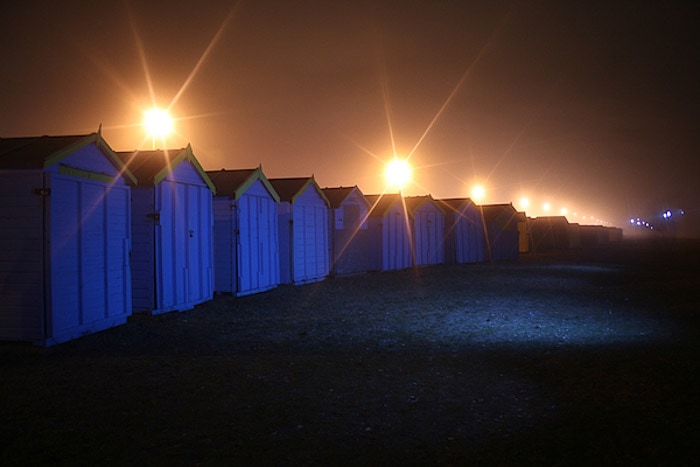 Una toma de fotografía nocturna de una hilera de pequeñas cabañas de madera