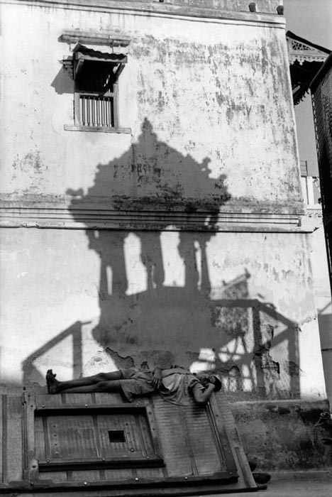 uma foto de henri cartier-bresson de um homem deitado do lado de fora de um prédio