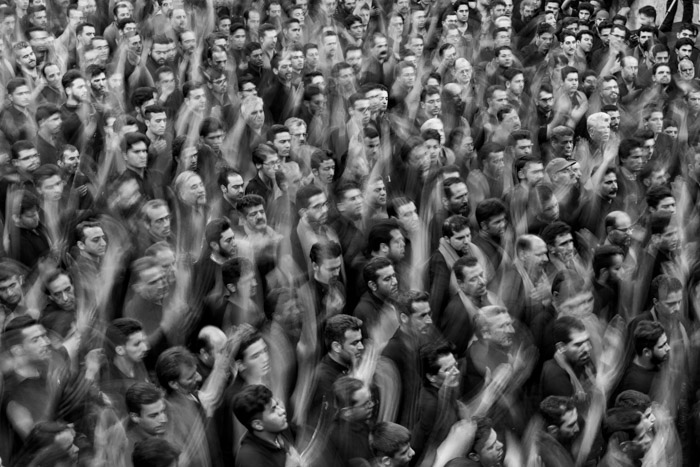 Uma foto em preto e branco de uma multidão de pessoas com as mãos levantadas no ar