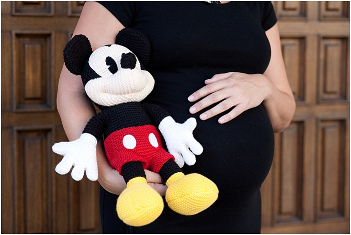 close up wanita hamil memegang perutnya, memegang boneka mickey mouse di sebelahnya