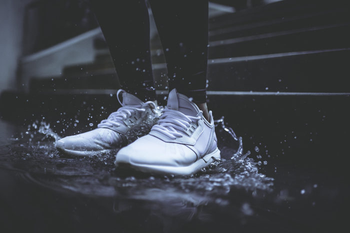 Dark and moody rain image of a persons feet stomping in a puddle