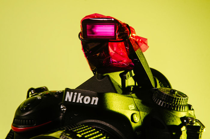 Close up van een Nikon-camera met roze cellofaan dat de flitser bedekt - kleurengelfotografie