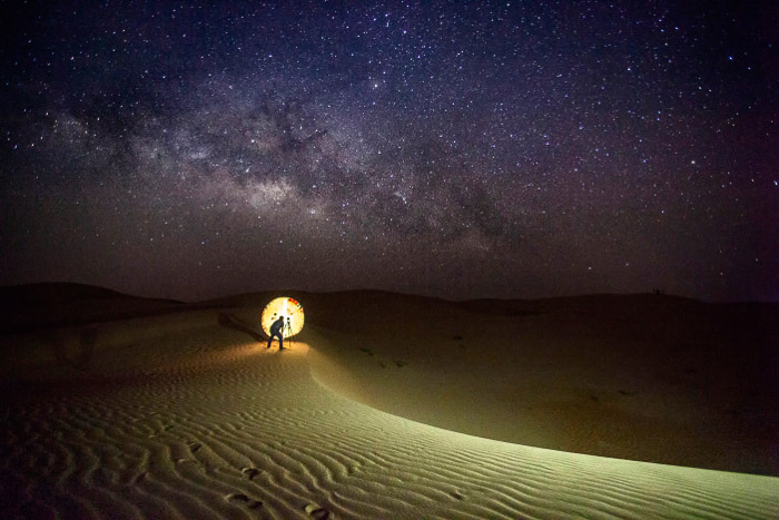 Fotograf ustawiający ujęcie do astrofotografii na pustyni