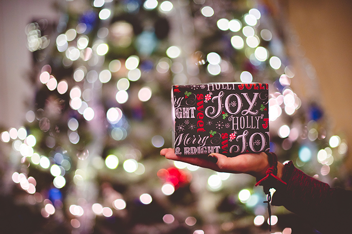 Lindas luzes de Natal bokeh no fundo de uma pessoa com um presente