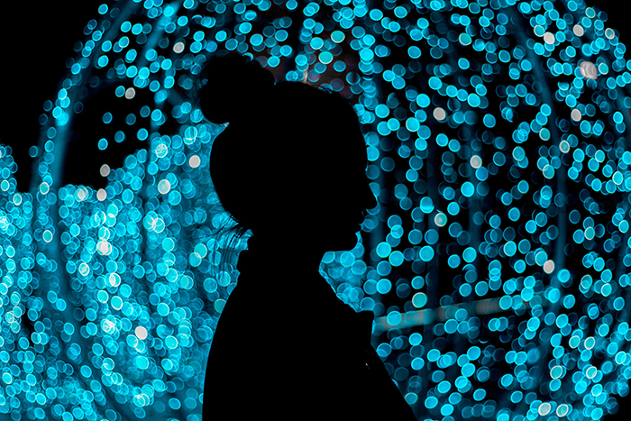 Uma silhueta de pessoas com fundo azul do bokeh das luzes de Natal