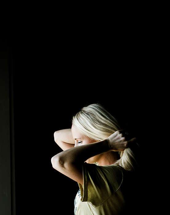  Atmosfærisk portrett av en kvinnelig modell som holder håret, skutt med chiaroscuro-belysning