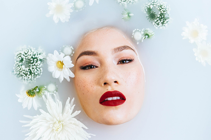 Linda fotografia de banho de leite de uma modelo feminina rodeada de flores brancas
