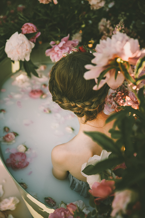 Linda fotografia de banho de leite de uma modelo feminina rodeada de flores 
