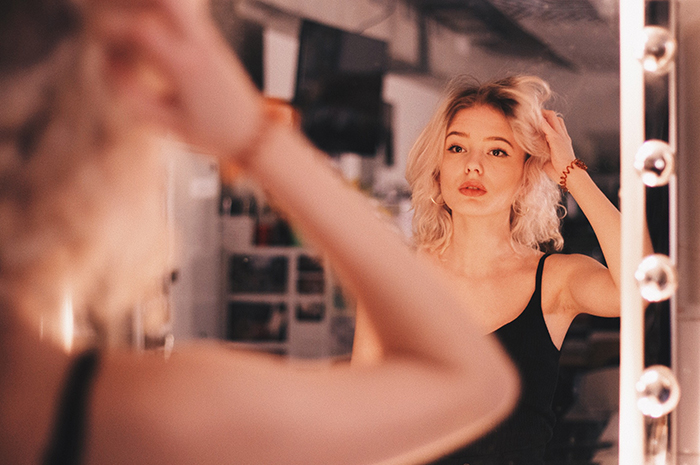 A portrait of a glamorous blonde model reflected in a Hollywood vanity mirror
