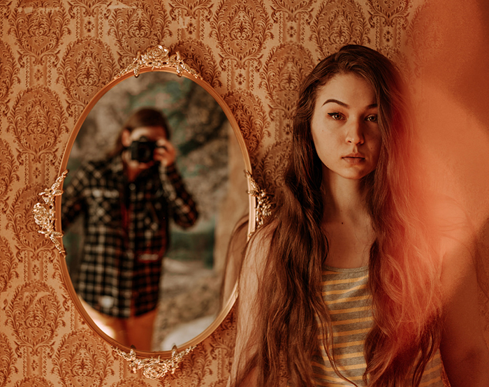 A diptych portrait of a brunette female model with the photographer reflected in a mirror 