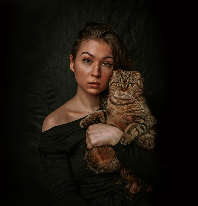 tunnelmallinen muotokuva naismallista pitelemässä ruskeaa kissaa 