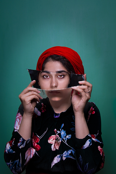 Un portrait coloré d'un modèle féminin tenant un miroir sur son visage - idées de photographie conceptuelle