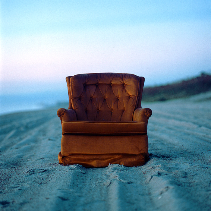 een rode bankstoel op het strand met behulp van filmfotografie