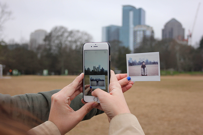 Close de uma pessoa tirando uma foto de uma polaroid impressa com um smartphone