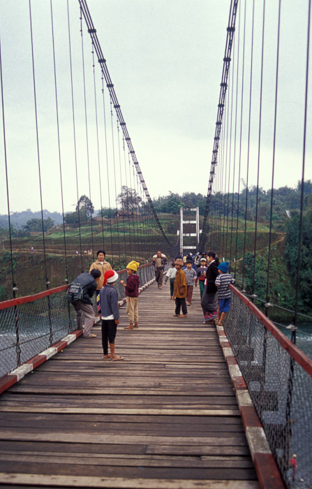 een groep mensen die een houten brug oversteekt