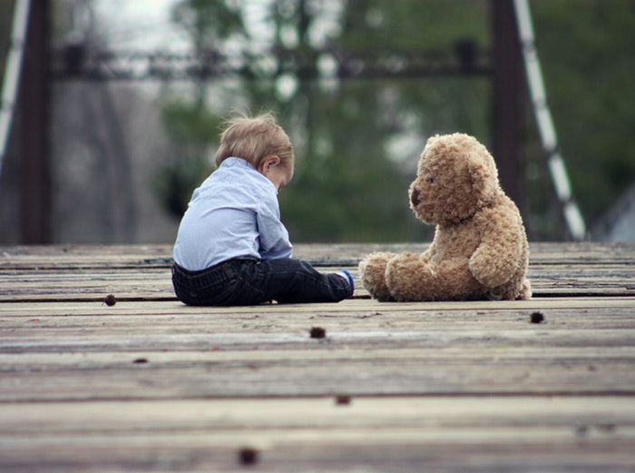 Un petit enfant assis avec un ours en peluche