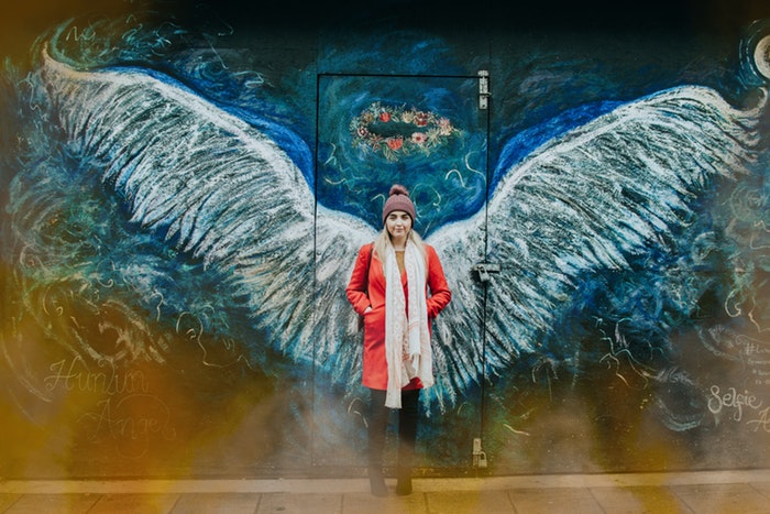 Femme debout devant un mur sur lequel sont dessinées des ailes d'ange