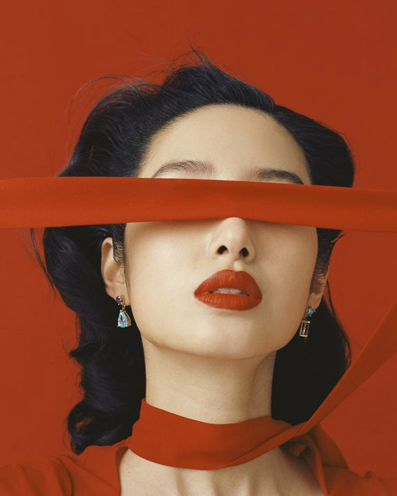 Seorang model fesyen dengan syal merah dengan latar belakang merah oleh Leslie Zhang misalnya