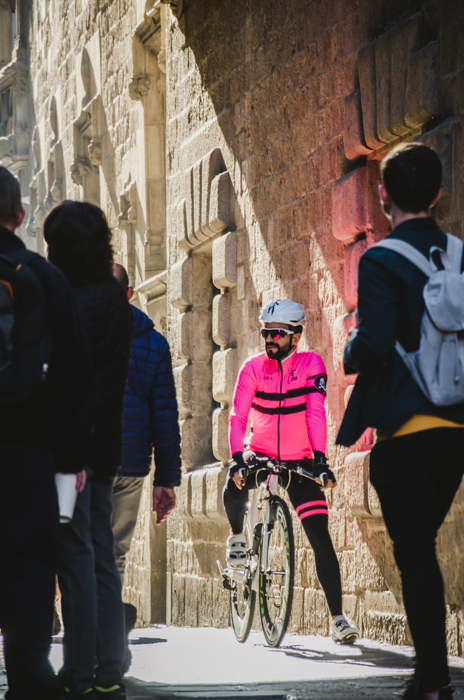 Street view di persone con focus su un motociclista in una giacca rosa
