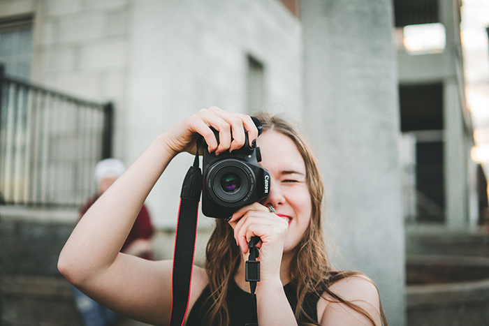 En kvindelig fotograf tager dimissionsbilleder med et canon dslr-kamera