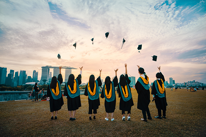 Un groupe d'étudiants en graduation lançant leur chapeau en l'air - photographie de graduation