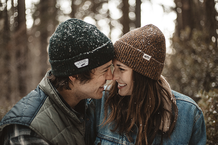 Ein lächelndes, fröhliches Paar im Schnee - lächeln Sie für die Kamera