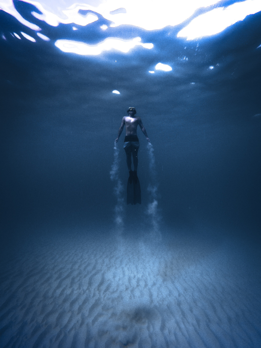 ett undervattensporträtt av en dykare med subtil vinjett på bilden