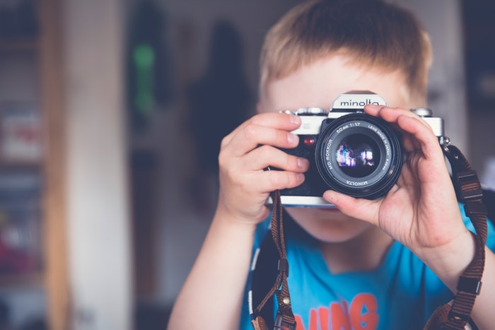 a little boy taking photos with a minolta camera