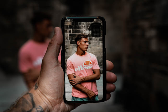 uma pessoa tirando um retrato de uma rua com uma câmera de smartphone
