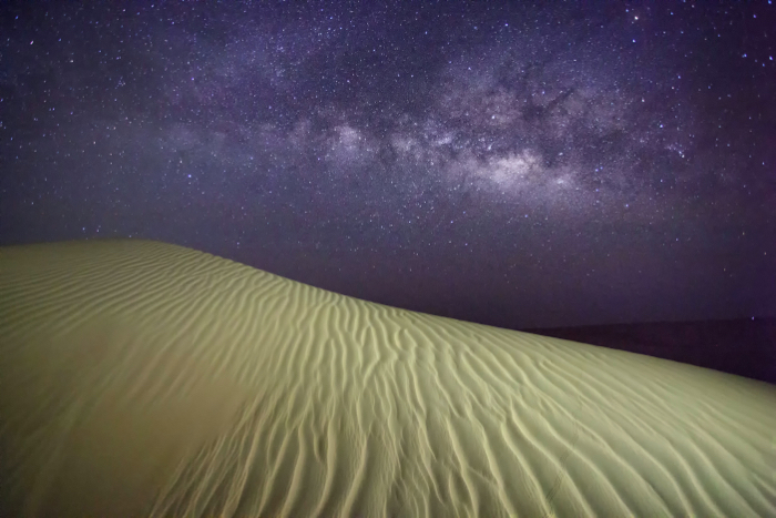 Astrophotography shot of a desert and the night sky above with stars and the milkyway