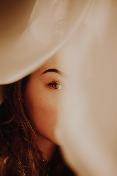 Portrait photo of a woman shot through white curtains as a frame