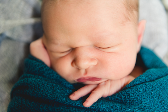 Foto de close-up de um bebê recém-nascido enrolado em um cobertor turquesa 