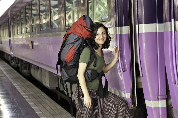 Foto seorang backpacker berdiri di samping kereta api