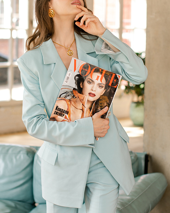 Foto seorang wanita berjas biru memegang majalah Vogue