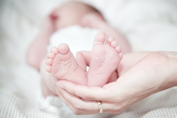 Close de mãos segurando os pés do bebê 