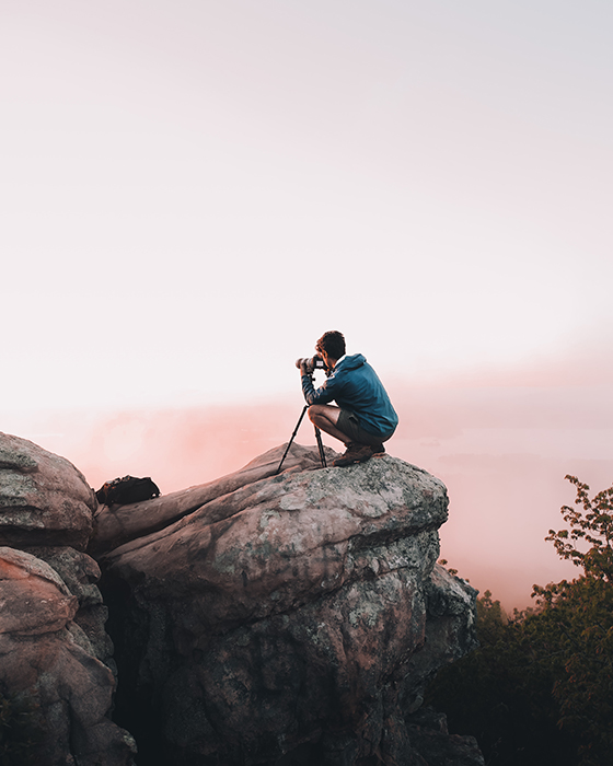 Photo of a man taking a photo on a rock