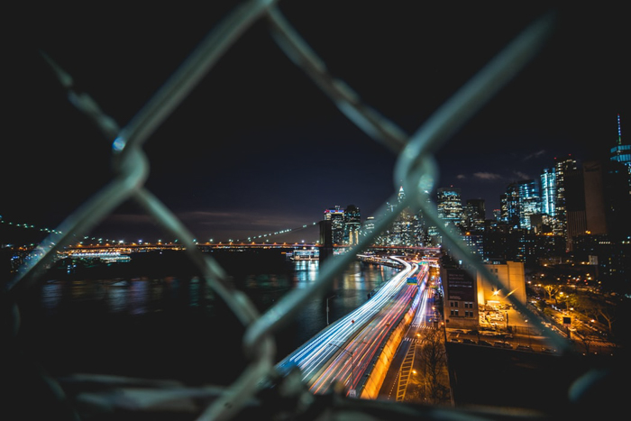 Noční snímek městské krajiny přes řetězový plot