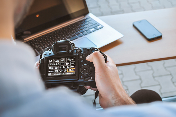 Um fotógrafo ajustando as definições da câmara numa Canon DSLR