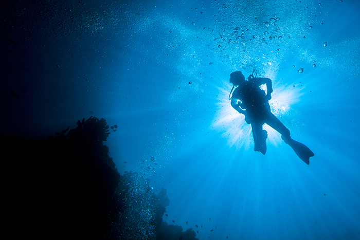 dykare fotograferad under vattnet i en negativ rymdkomposition.