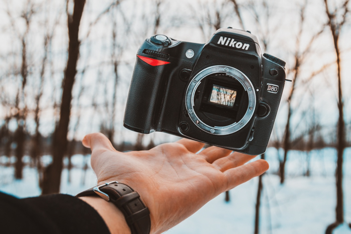 A hand balancing a Nikon DSLR camera body