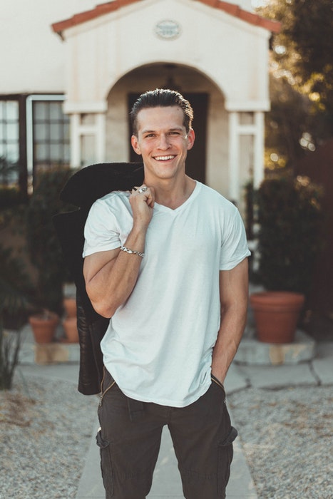 A man in white t-shirt posing casually outdoors