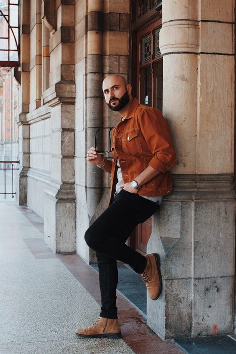 A man in casual dress posing casually against a wall