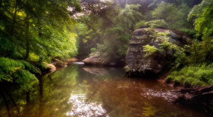 Bilde av en liten innsjø i en skog med orton effekt