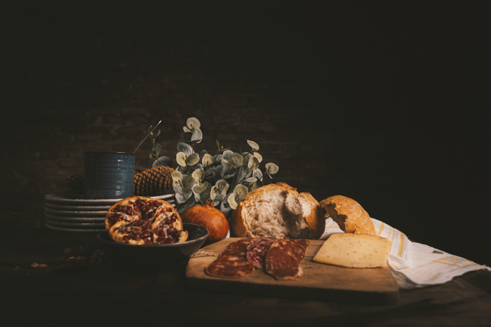 Foto de natureza morta com brad, presunto, queijo e pratos em uma mesa