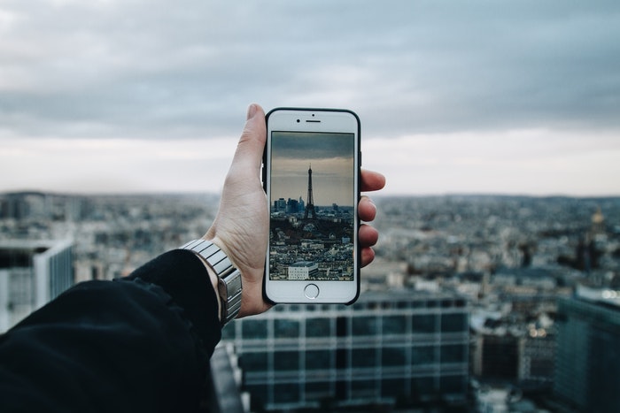 Uma pessoa tirando uma foto da Torre Eiffel com um smartphone.