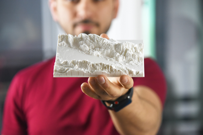 uma foto de uma nan segurando uma impressão 3D da paisagem 