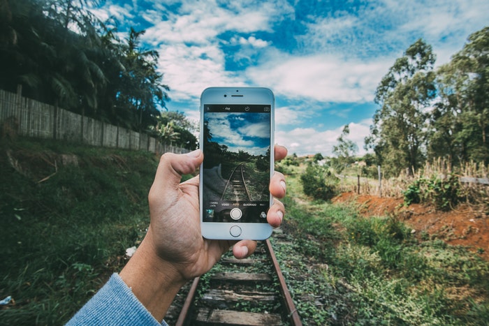 Uma pessoa tirando uma foto dos trilhos do trem com um smartphone
