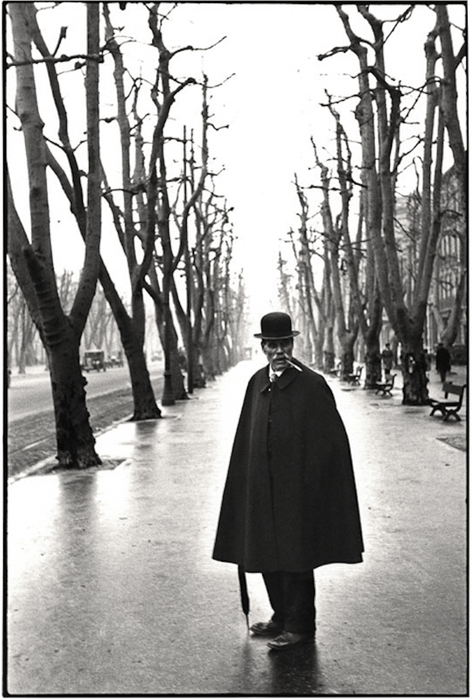 uma imagem em preto e branco de henri cartier-bresson de um homem dentro de duas fileiras de árvores